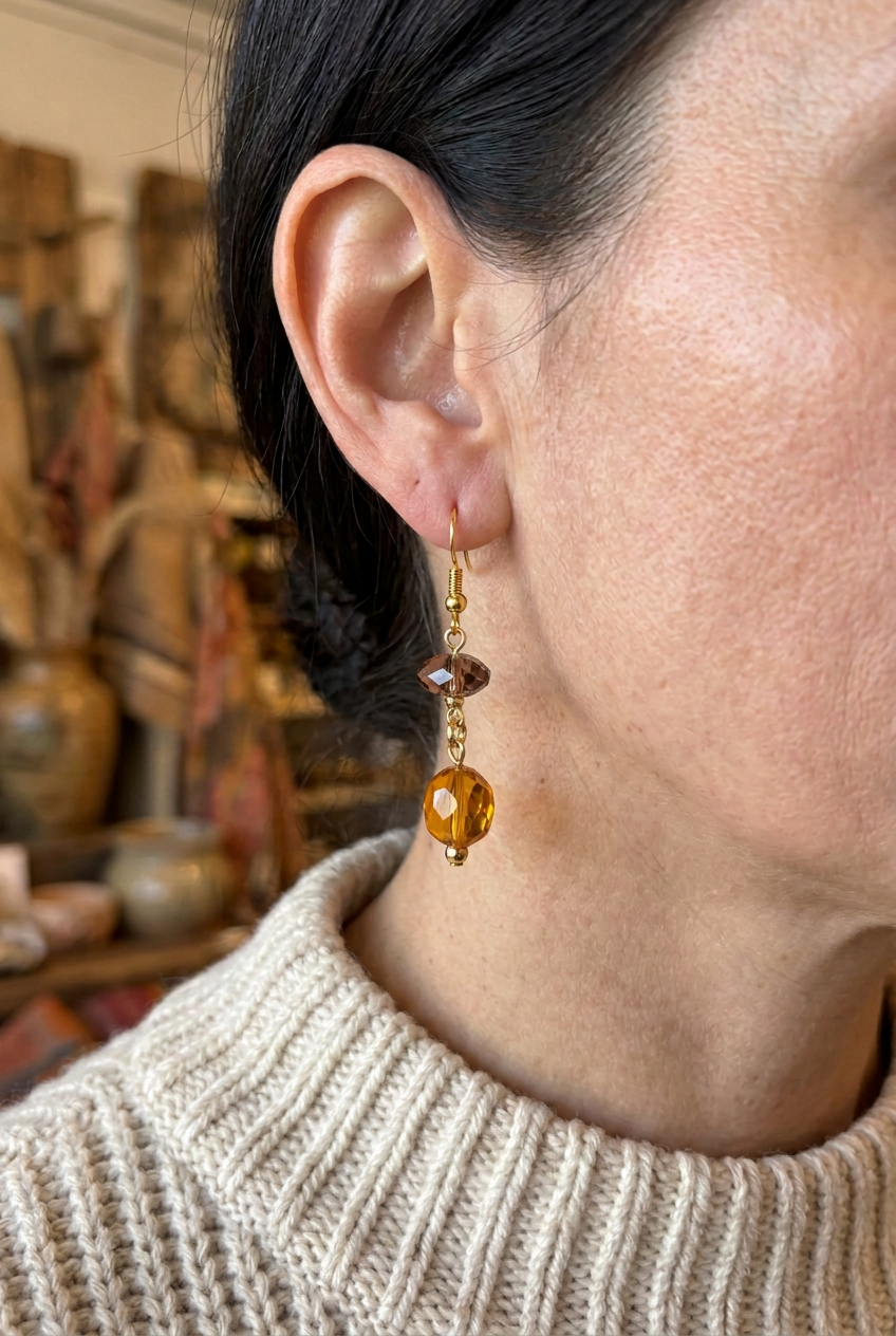 Woman wearing a honey-amber glass bead dangle earring with a smoky rose-brown accent bead and gold hook
