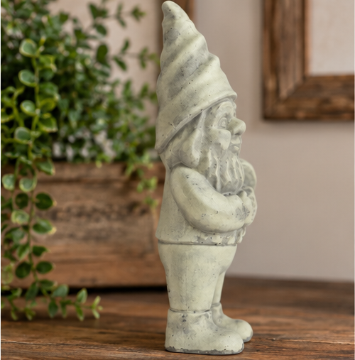 Side view of gray cement garden gnome with a tall pointed hat, beard, and boots on a wooden surface