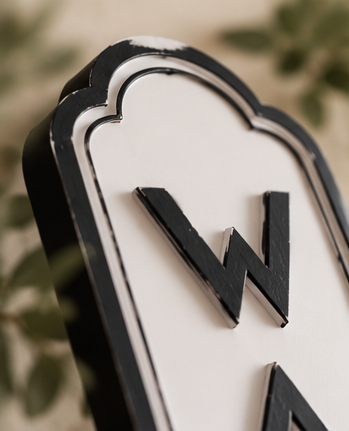 Close-up of the Wash laundry sign with raised black lettering and a curved black-and-white border