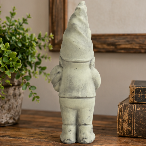 Rear view of Clifford cement garden gnome with a pointed hat and sculpted boots on a rustic tabletop