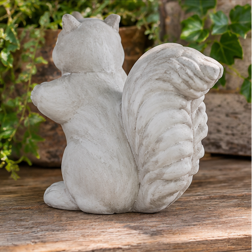 Rear view of gray cement squirrel statue with a sculpted bushy tail on a wooden surface