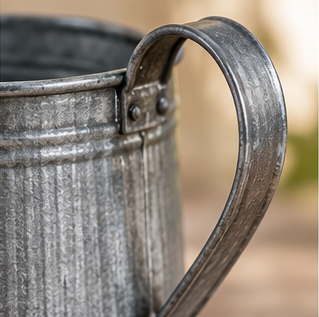 Close-up of the mini watering can’s curved metal handle and riveted attachment