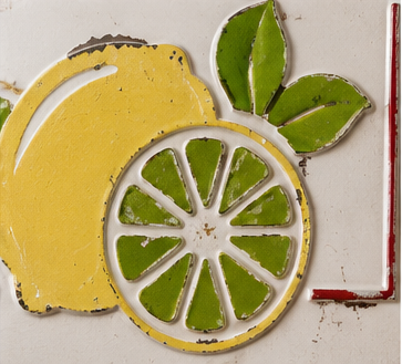 Close-up of the raised yellow lemon and green citrus slices and leaves on the Lemonade metal sign