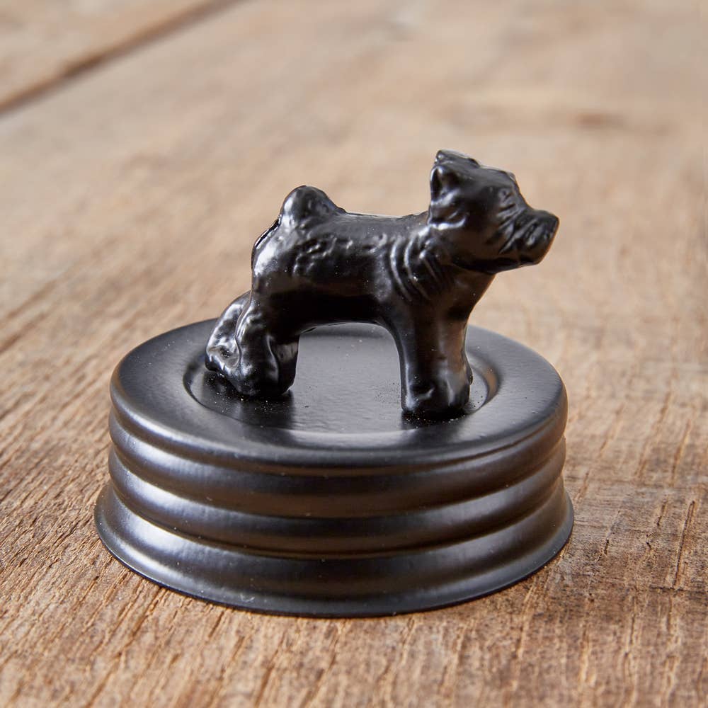 Black metal dog treat jar lid with a bulldog figurine displayed separately on a wooden surface