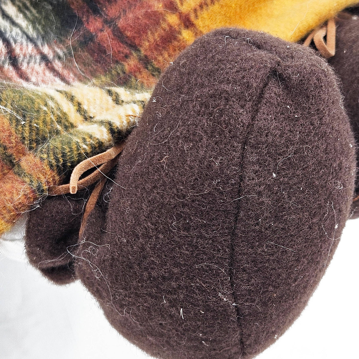 Close-up of the harvest gnome’s rounded brown fabric boot beneath its autumn plaid outfit