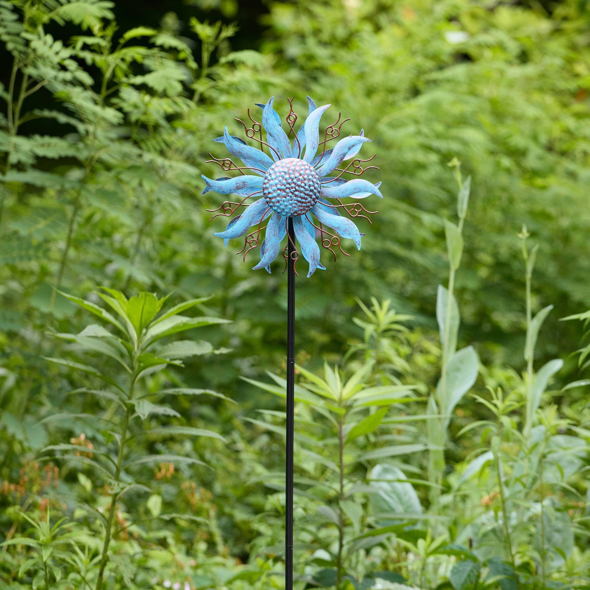 Close-up of blue coneflower wind spinner head with bokeh green garden background
