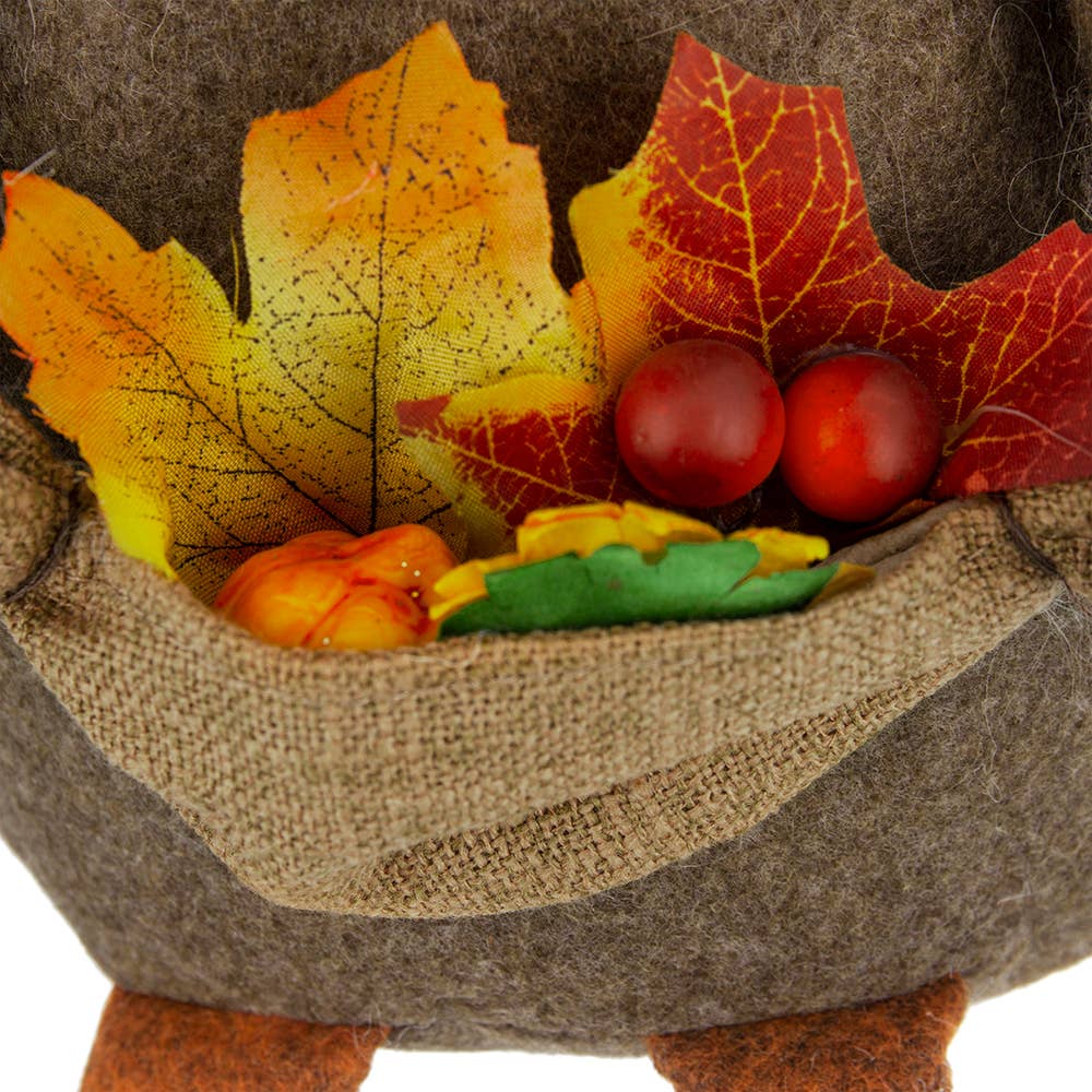 Close-up of the scarecrow gnome’s burlap pouch filled with decorative autumn leaves and berries