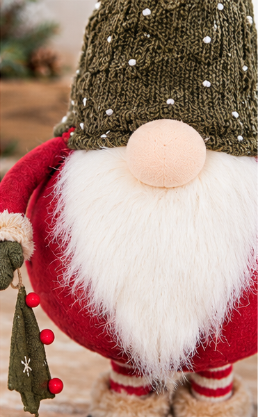 Close-up of the Tree Gift gnome’s green dotted knit hat, round nose, fluffy white beard, and red outfit