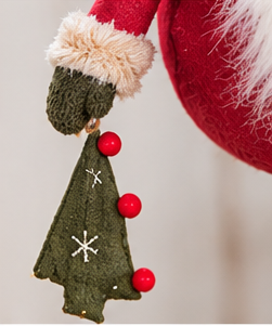 Close-up of the gnome’s hanging green fabric tree ornament with white stitched stars and red pompom accents