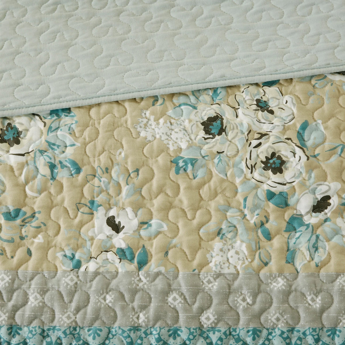Close-up of the Madison Park coverlet’s floral print, curved quilting, and pale aqua reverse.