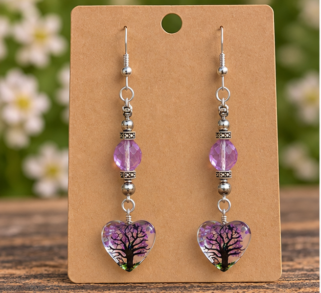 Handmade purple glass bead earrings with tree heart pendants and sterling silver hooks displayed on a kraft jewelry card