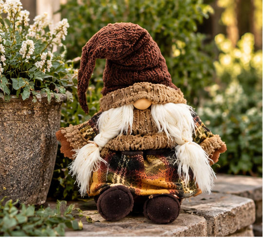 Rustic Harvest Gnome Plush on an aged brick garden ledge beside white flowers and lush greenery
