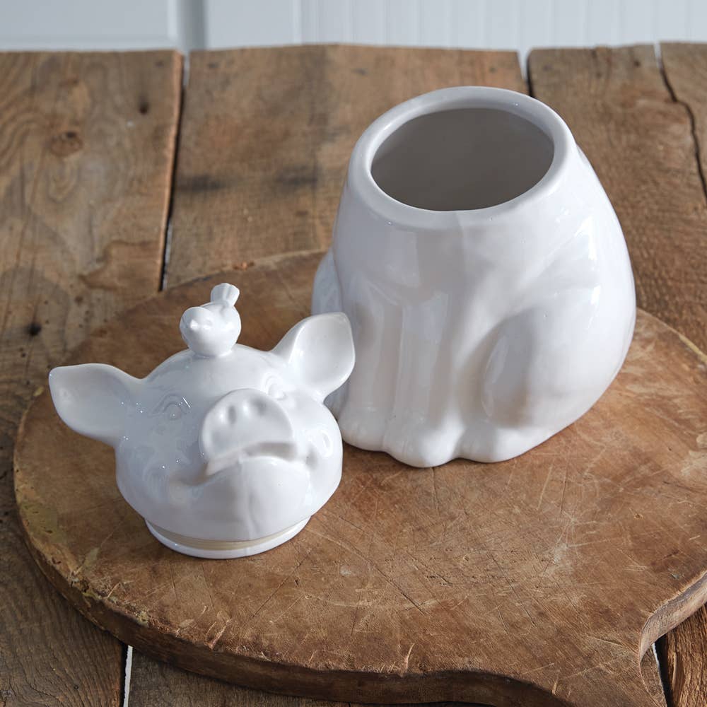 White ceramic piglet cookie jar with the pig-shaped lid removed, revealing the storage opening and rubber lid seal.