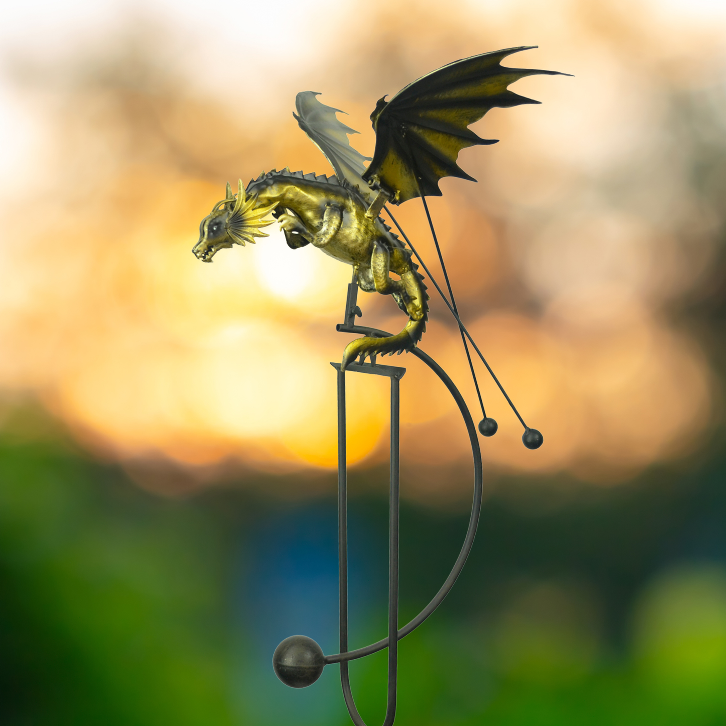 Gold dragon kinetic balance rocker garden stake in sunset garden setting, wings spread and body rocking on metal stake, 51 inches tall