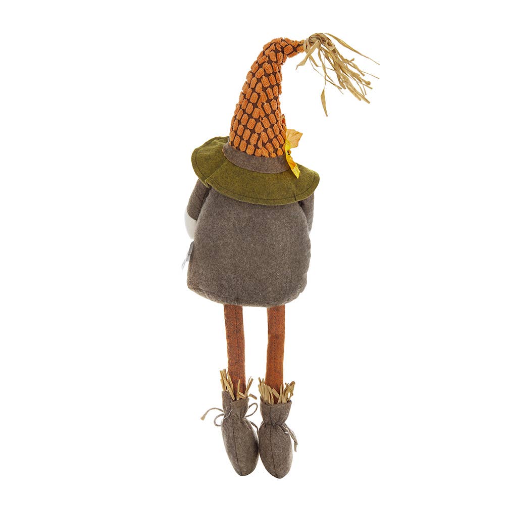 Rear view of the Harvest Scarecrow Gnome Plush with a green hat brim, gray-brown body, orange legs, and straw-trimmed boots