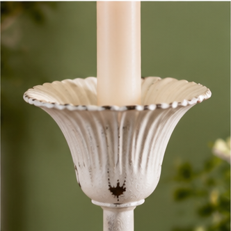 Close-up of an Evelyn candle holder’s fluted cup with a scalloped rim and distressed white finish