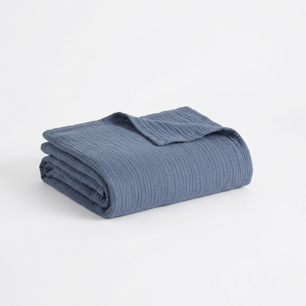 Close-up of the Clean Spaces denim-blue blanket’s softly crinkled cotton gauze texture.