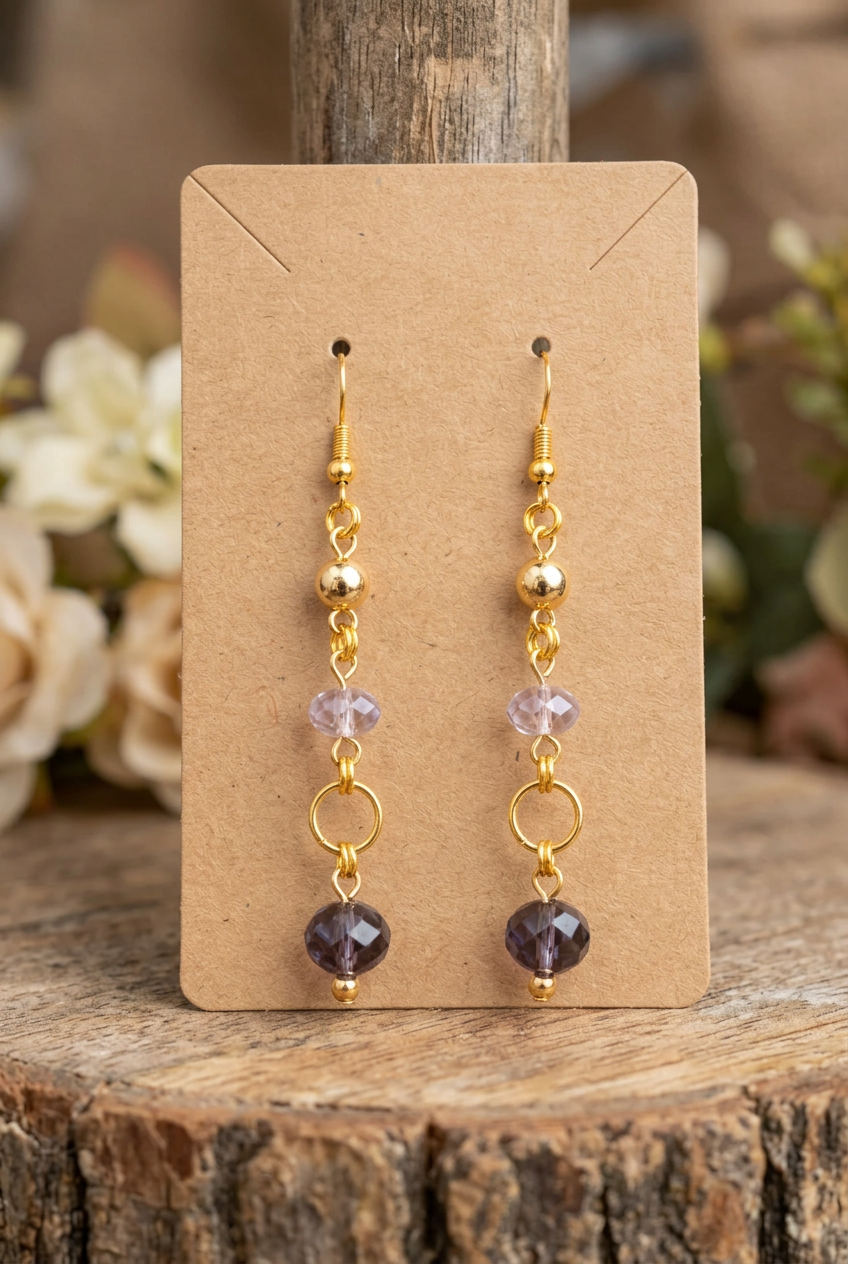 Handmade lavender and smoky purple glass bead earrings with gold accents and open circle links displayed on a kraft jewelry card