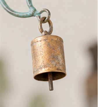 Close-up of a brass bell and clapper attached to the teal patina sun-and-moon wind chime.