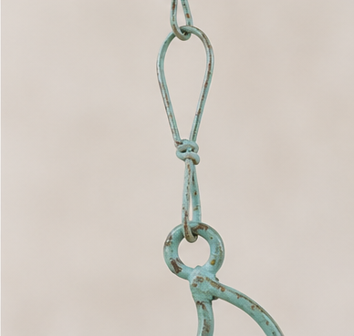 Close-up of the teal patina hanging chain and connecting ring on the sun-and-moon wind chime.