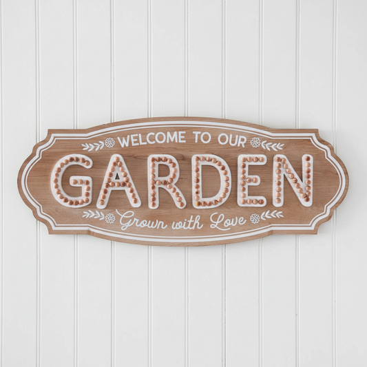 Rustic "Welcome to Our Garden" wood sign displayed on a white shiplap wall, 36"W × 14.5"H farmhouse garden decor with weathered finish and triangle hangers. CTW Home Collection